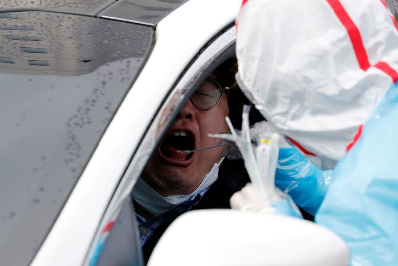 FILE PHOTO: A medical staff member in protective gear uses a swab to take samples from a visitor at 'drive-thru' testing center for the novel coronavirus disease of COVID-19 in Yeungnam University Medical Center in Daegu