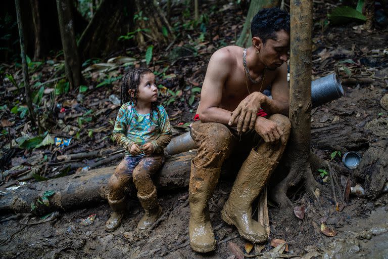 Un hombre y un niño exhaustos en el Tapón del Darién, con una semana de caminata por delante a través del tramo de decenas de kilómetros de terreno selvático entre Colombia y Panamá. (Federico Rios/The New York Times)