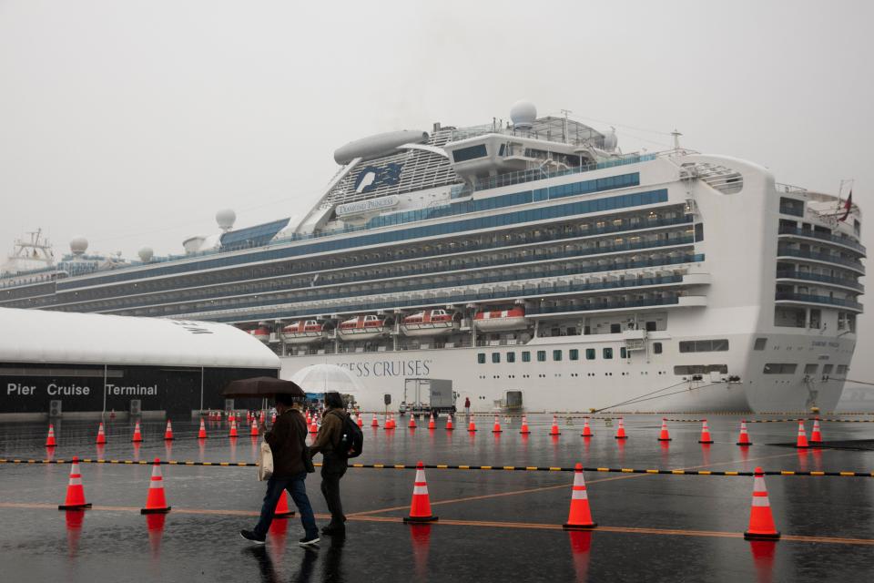 Visitors walk past the quarantined Diamond Princess cruise ship in Yokohama, near Tokyo. Americans who have not testes positive for the virus will be flown back home on chartered flights Sunday, but will face another two-week quarantine. (ASSOCIATED PRESS)