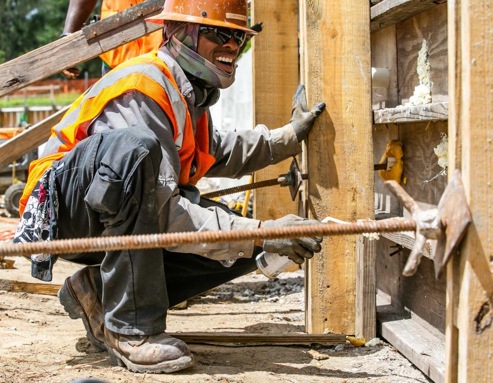 Construction worker Dwayne Larry with RWH Construction sprays expansion foam in the holes of a form while busy assembling forms in 2021.