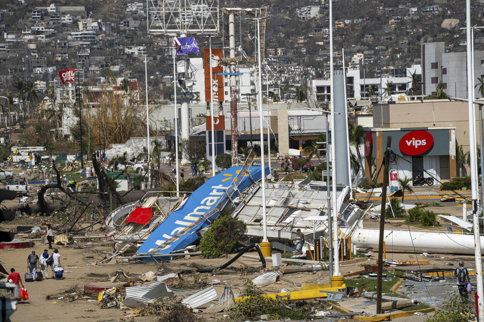 Residentes caminan entre los escombros que dejó el paso del devastador huracán Otis, de categoría 5, en Acapulco, México, el viernes 27 de octubre de 2023. (AP Foto/Félix Márquez)