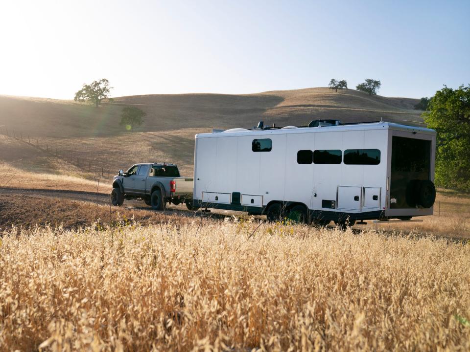 The travel trailer being towed by a truck on a field.