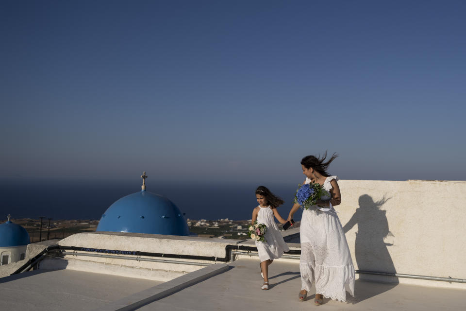 Cinzia Sansone y su hija Josephine, de Trieste (Italia) fotografiadas en una terraza desde la que se divisa el Monasterio Católico de Santa Catalina en la isla griega de Santorini el 14 de junio de 2022. (Foto AP/Petros Giannakouris)