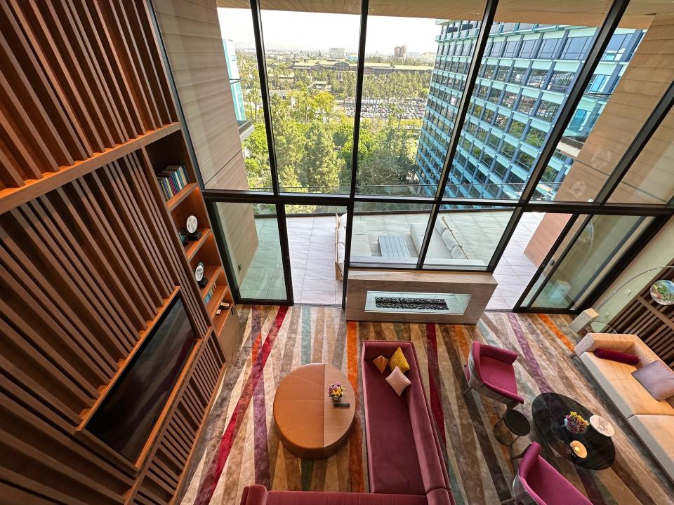 Two-story window with black dividers with a double-sided fireplace next to wood-decorated wall in Disneyland villa