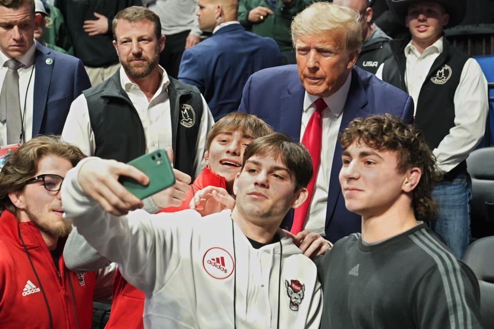 Former President Donald J. Trump, right, poses for photos at the NCAA Wrestling Championships, Saturday, March 18, 2023, in Tulsa, Okla. At left is U.S. Sen. Markwayne Mullin. (AP Photo/Sue Ogrocki)
