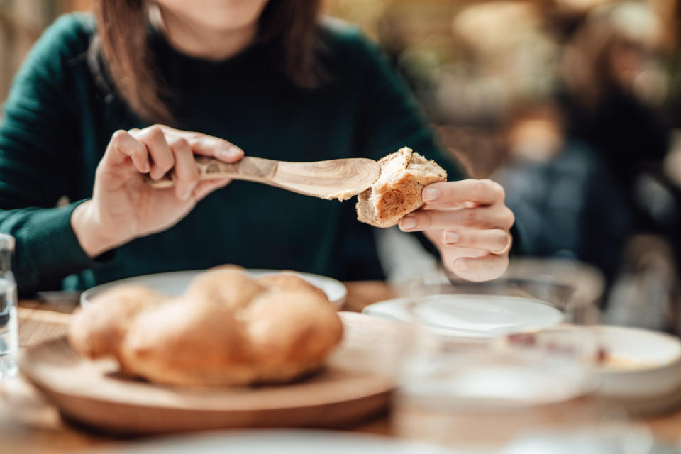 A woman buttering bread at a table.