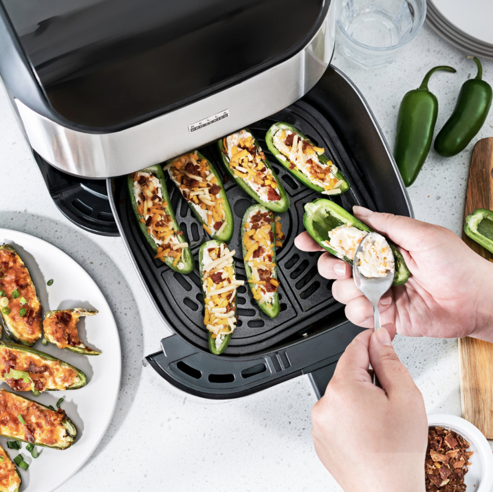 Bella Pro Touchscreen Air Fryer - 5.7L with hand putting food inside (Photo via Best Buy Canada)