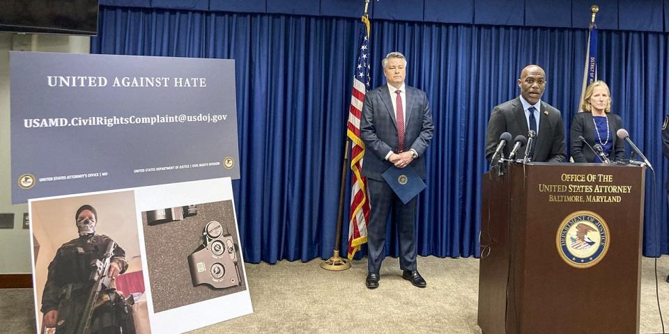 A US attorney stands in front of a podium during a press conference next to evidence.