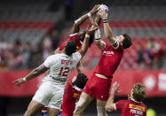 United States' Martin Iosefo (12) vies for the ball against Canada's Andrew Coe, right, and Josiah Morra, back, during an HSBC Canada Sevens rugby game in Vancouver, British Columbia, Saturday, Sept. 18, 2021. (Darryl Dyck/The Canadian Press via AP)