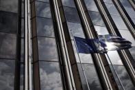 A European Union flag (L) and a Greek national flag flutter as the sky is reflected on a building front in Athens February 17, 2015. REUTERS/ Alkis Konstantinidis