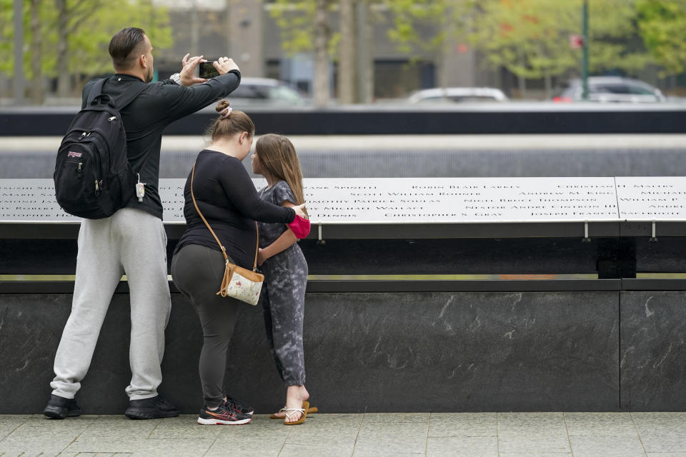 Visitors to the 9/11 Memorial and Museum take in the view of the North Pool, Thursday, April 29, 2021, in New York. In recent weeks, tourism indicators for New York City like hotel occupancy and museum attendance that had fallen off a pandemic cliff have ticked up slightly. It's a welcome sight for a city where the industry has been decimated by the impact of the coronavirus. (AP Photo/Mary Altaffer)