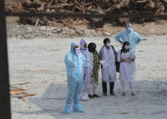 Family members wait to cremate body of a COVID-19 victim at an open crematorium set up at a granite quarry on the outskirts of Bengaluru, India, Wednesday, May 5, 2021. (AP Photo/Aijaz Rahi)