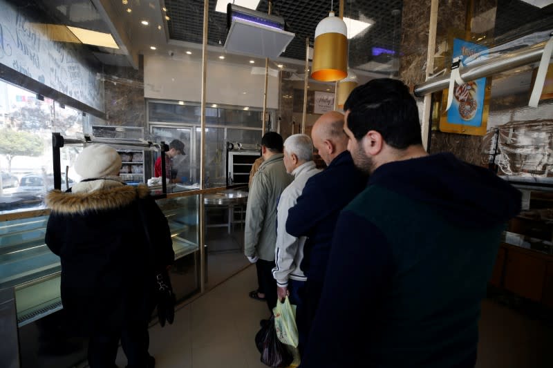 Palestinians stand in line as they wait to buy bread at a bakery amid concerns over the spread of the coronavirus disease, in Gaza City