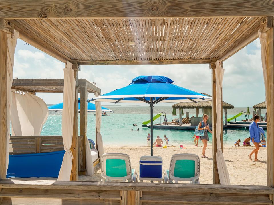A view of the shore at the beach through an empty cabana on a cloudy day at CocoCay