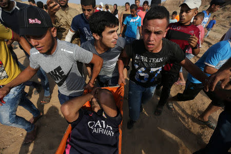 A wounded Palestinian protester is evacuated during clashes with Israeli troops near the border between Israel and central Gaza Strip July 21, 2017. REUTERS/Ibraheem Abu Mustafa