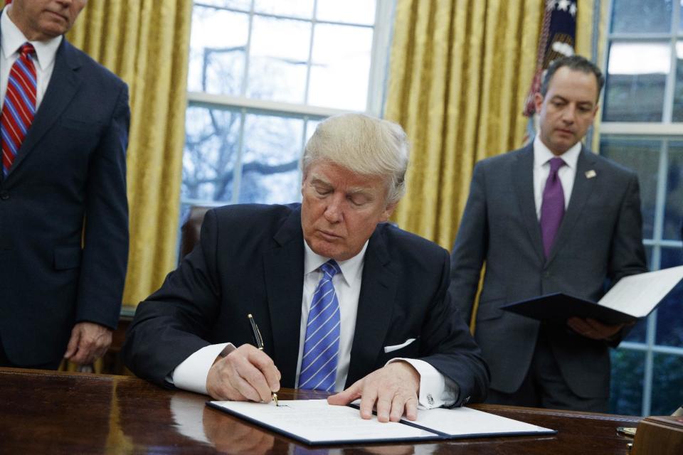 FILE - In this Jan. 23, 2017, file photo, President Donald Trump signs an executive order to withdraw the U.S. from the 12-nation Trans-Pacific Partnership trade pact agreed to under the Obama administration in the Oval Office of the White House in Washington. (AP Photo/Evan Vucci, File)