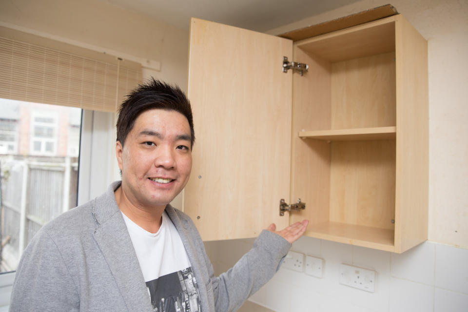 Khai Ho shows his empty kitchen cupboards. (Caters)