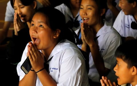 Classmates pray after their teacher announced some of the 12 schoolboys trapped inside a flooded cave, have been rescued - Credit: TYRONE SIU /Reuters