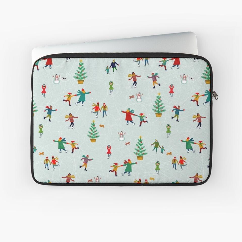 A laptop sleeve with a pale green background with ice skaters, trees and snowmen