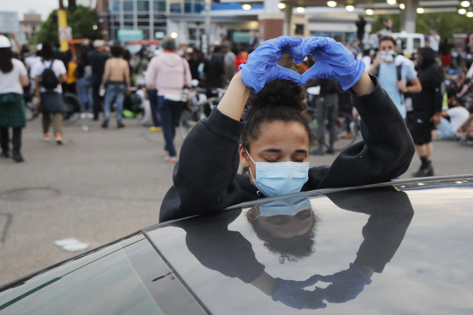 A demonstrator makes a heart sign while protesting after curfew Sunday, May 31, 2020, in Minneapolis.Protests continued following the death of George Floyd, who died after being restrained by Minneapolis police officers on Memorial Day. (AP Photo/Julio Cortez)