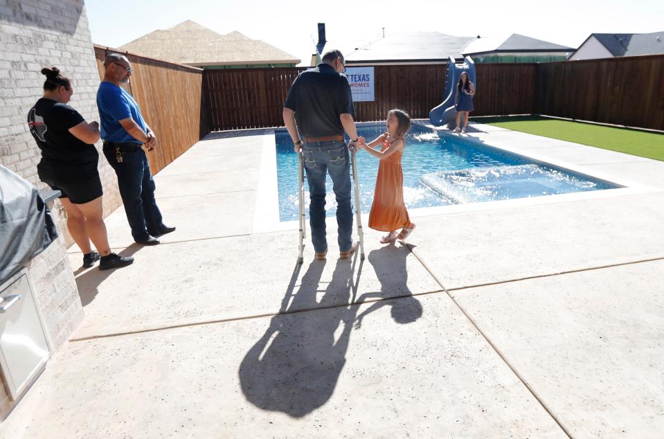 Lubbock Fire Rescue firefighter Matt Dawson and his 7 year-old daughter Preslee Dawson look over the backyard of the new home that his family was presented with on Thursday, August 26, 2021. Dawson was struck by a vehicle in the line-of-duty on January 11, 2020.