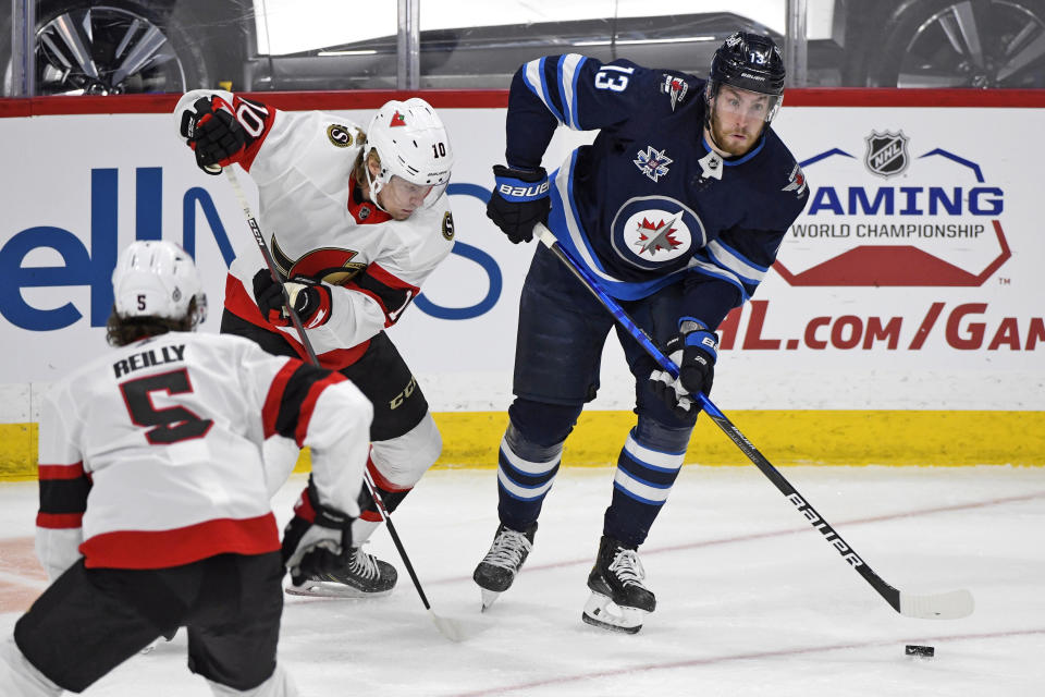 FILE - In this April 5, 2021, file photo, Winnipeg Jets' Pierre-Luc Dubois (13) looks to pass the puck past Ottawa Senators' Ryan Dzingel (10) during the first period of an NHL hockey game in Winnipeg, Manitoba. Dubois is looking forward to finally getting to know his Jets teammates after spending much of last season in Winnipeg isolated from them due to COVID-19 protocols coupled with a rash of injuries.(Fred Greenslade/The Canadian Press via AP, File)