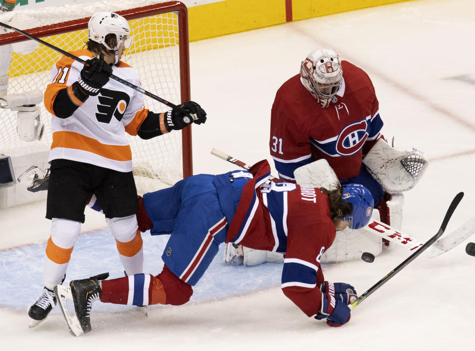 Montreal Canadiens defenseman Ben Chiarot (8) gets leveled by Philadelphia Flyers right wing Travis Konecny (11) as Canadiens goaltender Carey Price (31) makes a save during the second period of Game 3 of an NHL hockey playoff first-round series Sunday, Aug. 16, 2020, in Toronto. (Frank Gunn/The Canadian Press via AP)