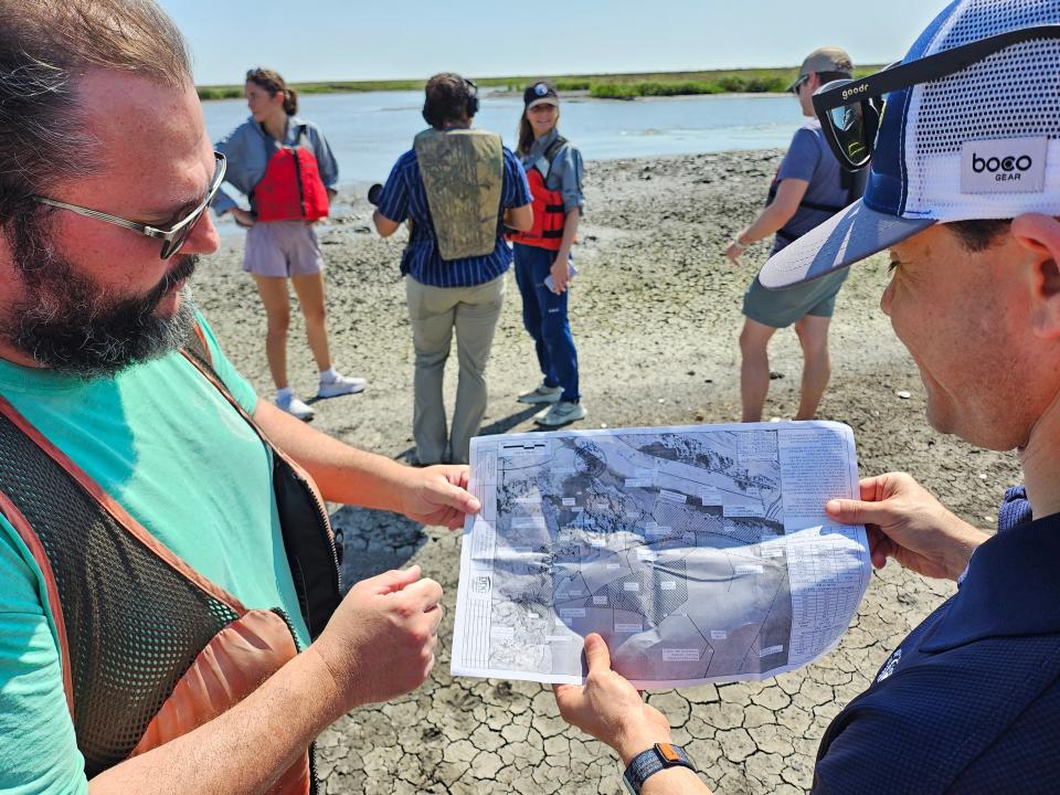 CPRA Executive Director Glenn Ledet Jr. and Construction manager Barry Richard show off a map of the $114 million Lake Borgne marsh restoration project, May 16, 2024. They are looking at the map standing on part of the marsh recently rebuilt.