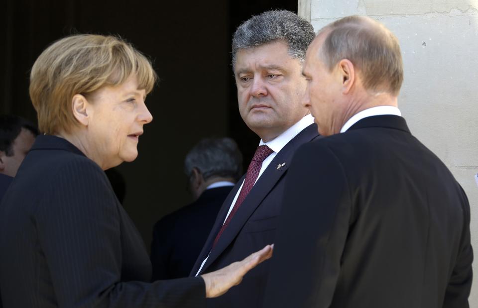 FILE - German Chancellor Angela Merkel, left, Russian President Vladimir Putin, right, and then Ukrainian president-elect Petro Poroshenko, center, talk at the 70th anniversary of D-Day in Benouville in Normandy, France, June 6, 2014. The Minsk agreement brokered by France and Germany, following painful defeats suffered by Ukrainian forces, obliged Kyiv to offer the separatist regions broad autonomy, including permission to form their own police force. (Regis Duvignau/Pool Photo via AP, File)