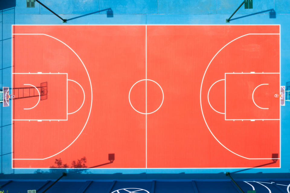 Aerial view of an empty basketball court with clear boundary lines and hoops at either end