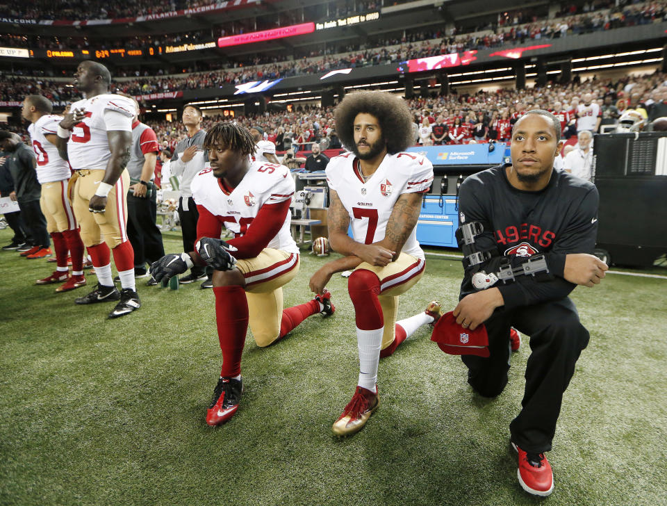 FILE - In this Dec. 18, 2016, file photo, San Francisco 49ers quarterback Colin Kaepernick (7) and outside linebacker Eli Harold (58) kneel during the playing of the national anthem before an NFL football game against the Atlanta Falcons in Atlanta. The blackballed quarterback was honored as Week 1 Community MVP by the players' union for his latest $100,000 donation and a back-to-school giveaway in New York City.  (AP Photo/John Bazemore, File)