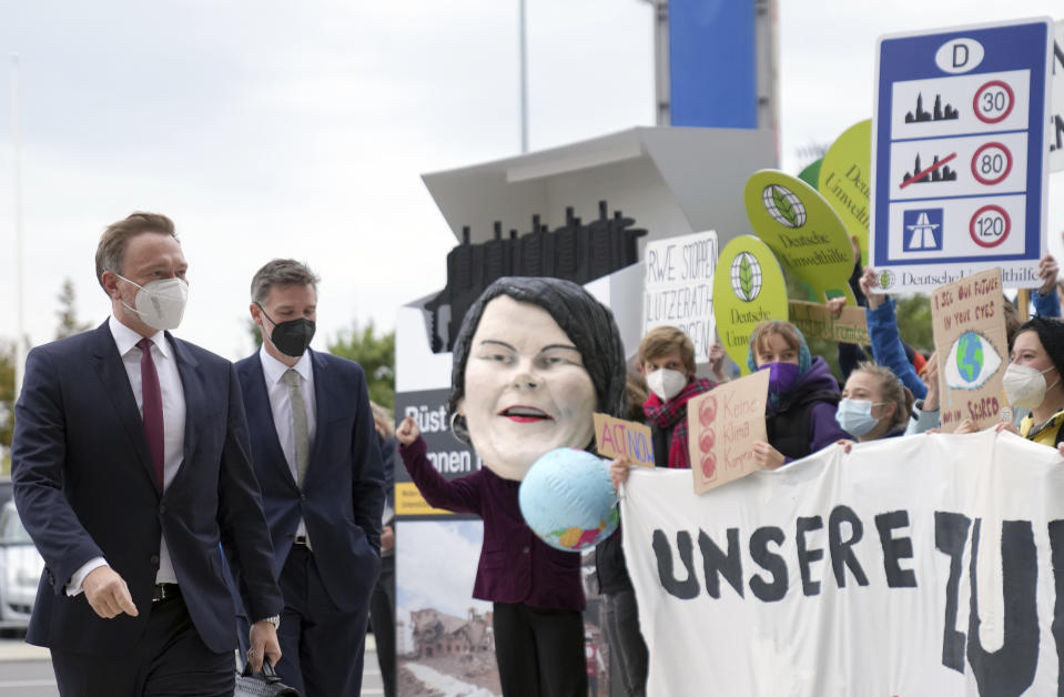 Christian Lindner (l), parliamentary group leader and party leader of the FDP, arrives at the venue for exploratory talks between the SPD, FDP and the Green Party on the formation of a new federal government after the Bundestag elections in Berlin, Germany, Friday, Oct. 15, 2021. He will be met by Fridays for Future activists, Greenpeace and the campaign organisation Campact, who are demonstrating for climate protection and against arms exports. The SPD, the Greens and the FDP want to agree on a basis for decision-making for coalition negotiations that summarises the outcome of the negotiations so far. (Kay Nietfeld/dpa via AP)