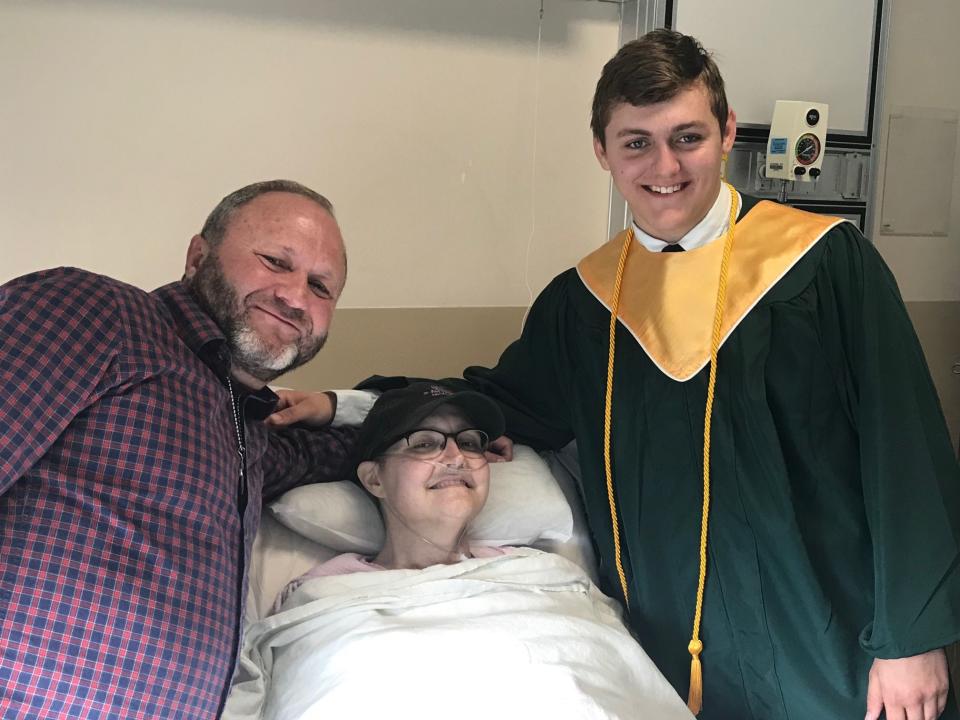 Johnny and Noah Siets pose at Marilyn's bedside during Noah's special graduation ceremony held in her hospital room.