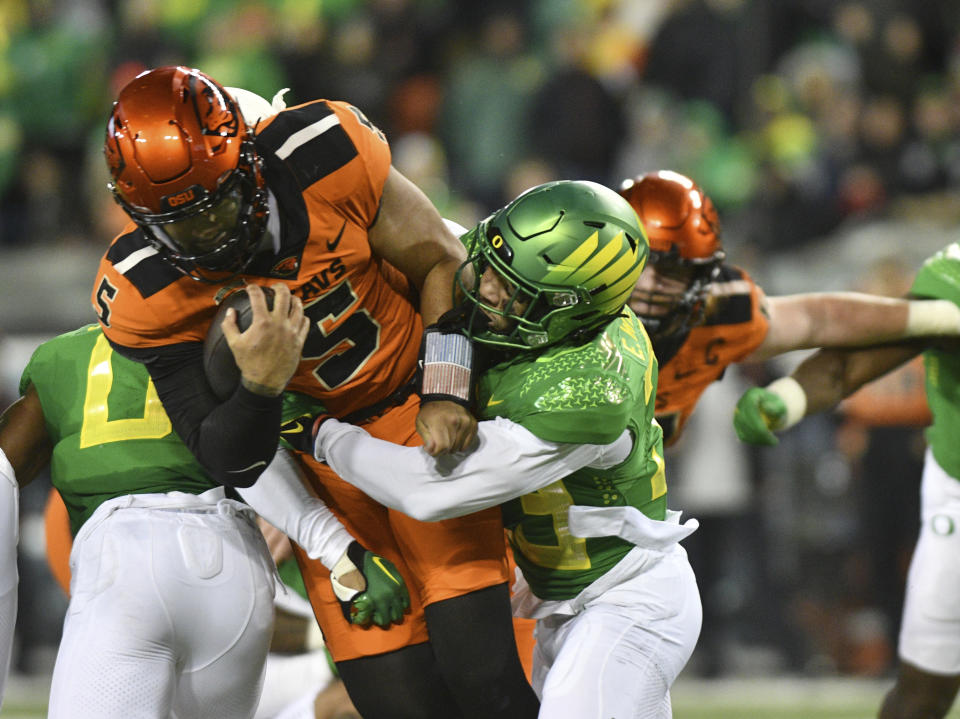 Oregon State quarterback DJ Uiagalelei (5) is tackled by Oregon defensive back Evan Williams, front right, during the first half of an NCAA college football game Friday, Nov. 24, 2023, in Eugene, Ore. (AP Photo/Mark Ylen)