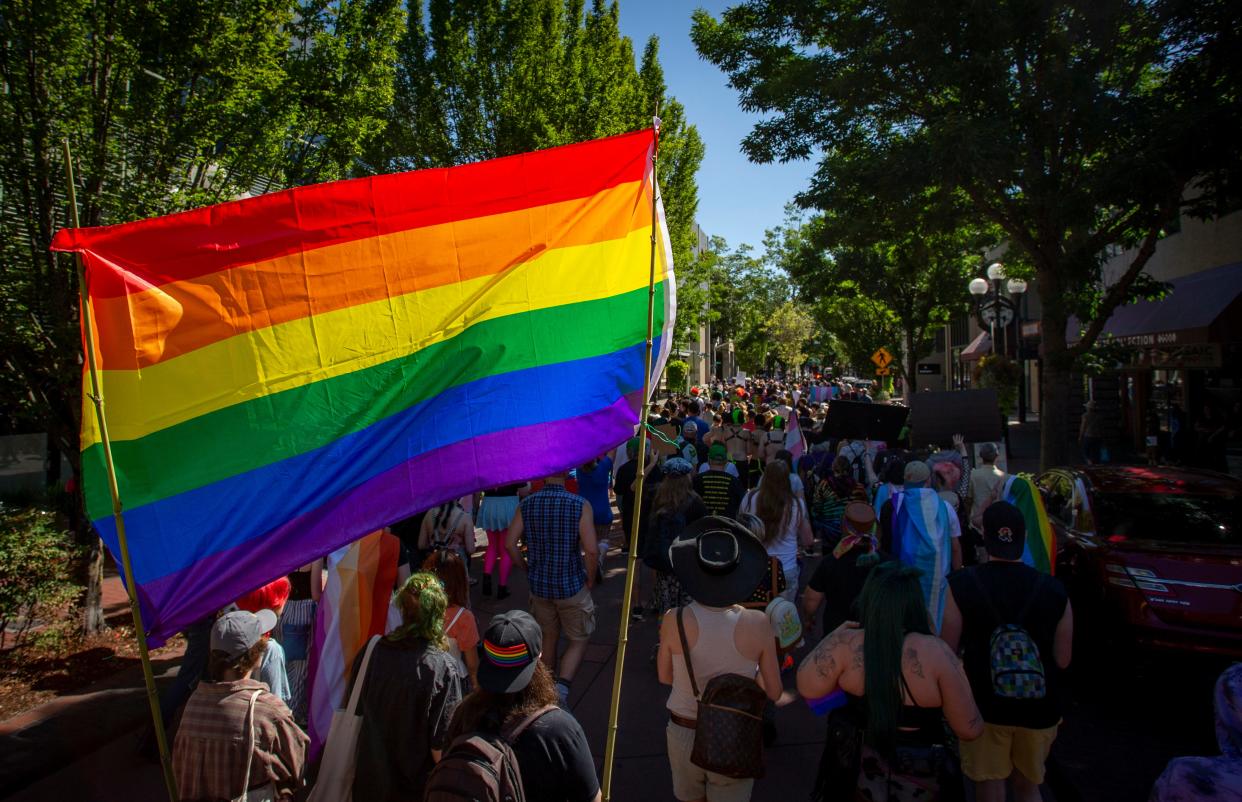 A large Pride flag hangs over marchers during Eugene’s Pride in the Park in 2022.