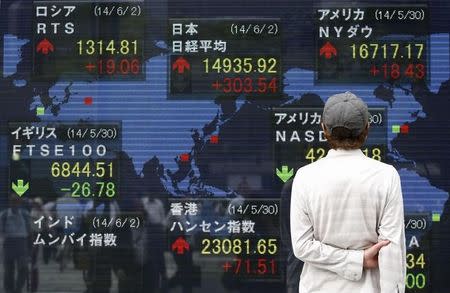 A pedestrian looks at an electronic board showing the stock market indices of various countries outside a brokerage in Tokyo June 2, 2014. REUTERS/Yuya Shino