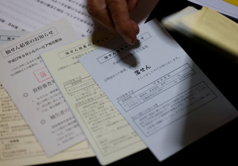 Pensioner Yoshio Koitabashi shows postcards he has received over the years notifying him of his unsuccessful attempts at winning the lottery to live in public housing, in Tokyo