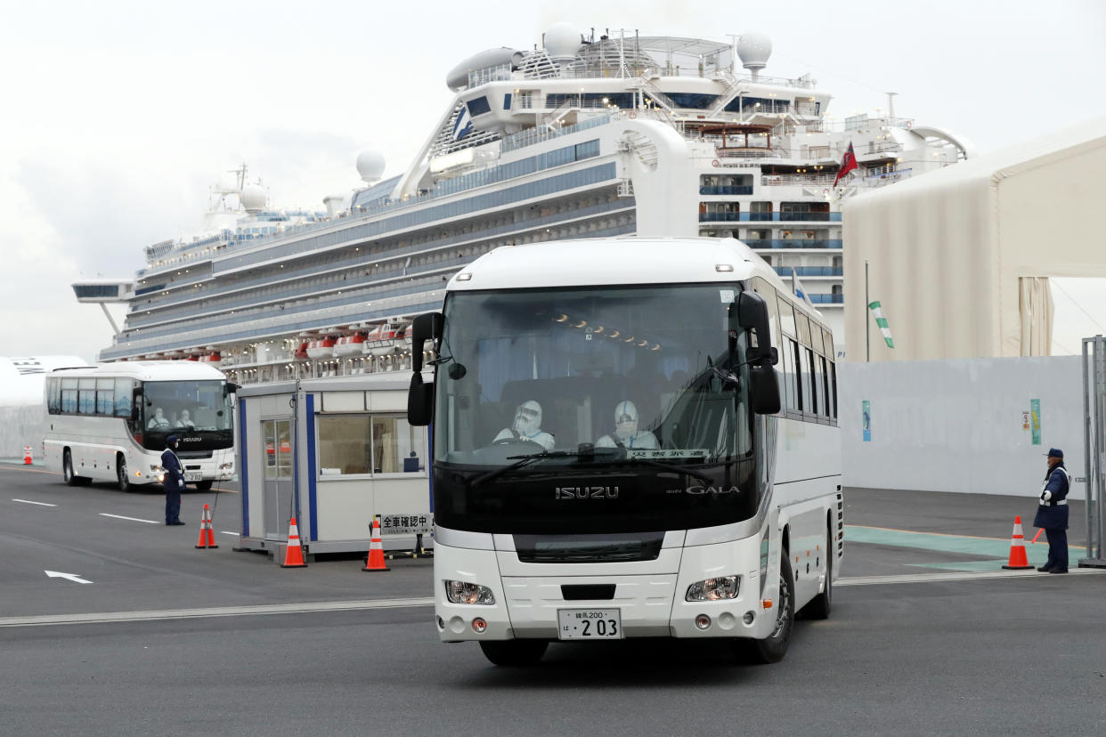 A bus carrying passengers from the quarantined Diamond Princess cruise ship leaves a port in Yokohama, Japan