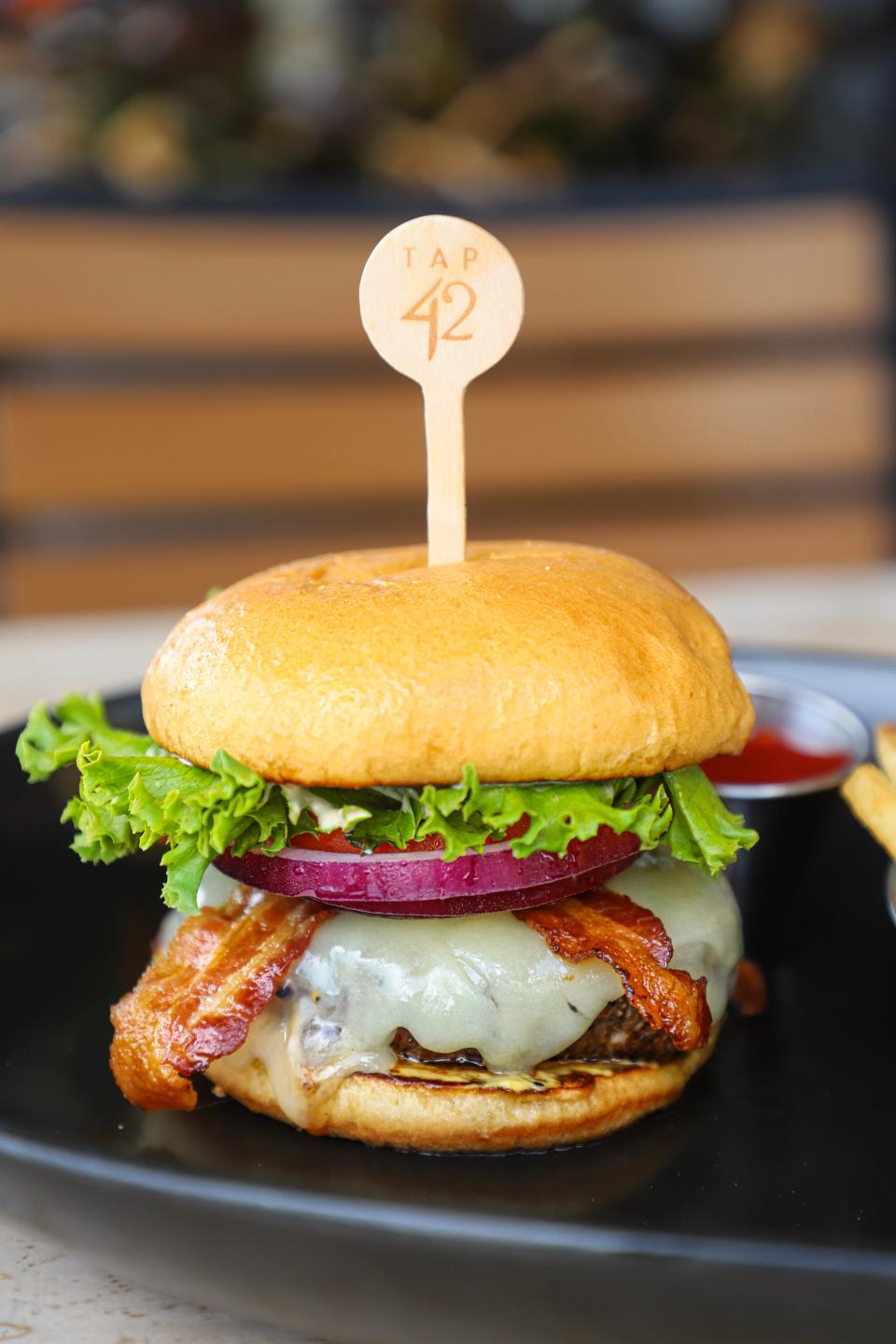 Tap 42's Prohibition Burger layers apple-wood bacon, white cheddar and other toppings over a burger-blend patty.