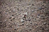 <p>A small boy holds a cardboard cover over his head to protect himself from the sun as he walks on the dried-up bed of river Tawi in Jammu, India, May 27, 2016. Temperatures across much of northern and western India have hovered around 40 degrees Celsius (104 degrees Fahrenheit) for weeks, causing much distress, specially inthe farming communities. (AP Photo/Channi Anand) </p>