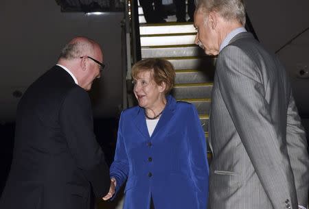 Germany's Chancellor Angela Merkel (C) shakes hands with Australia's Attorney-General George Brandis (L), as Germany's Ambassador to Australia Christoph Mueller looks on, after her arrival at the G20 Terminal in Brisbane in this November 14, 2014 picture provided by G20 Australia. REUTERS/G20 Australia/Handout via Reuters