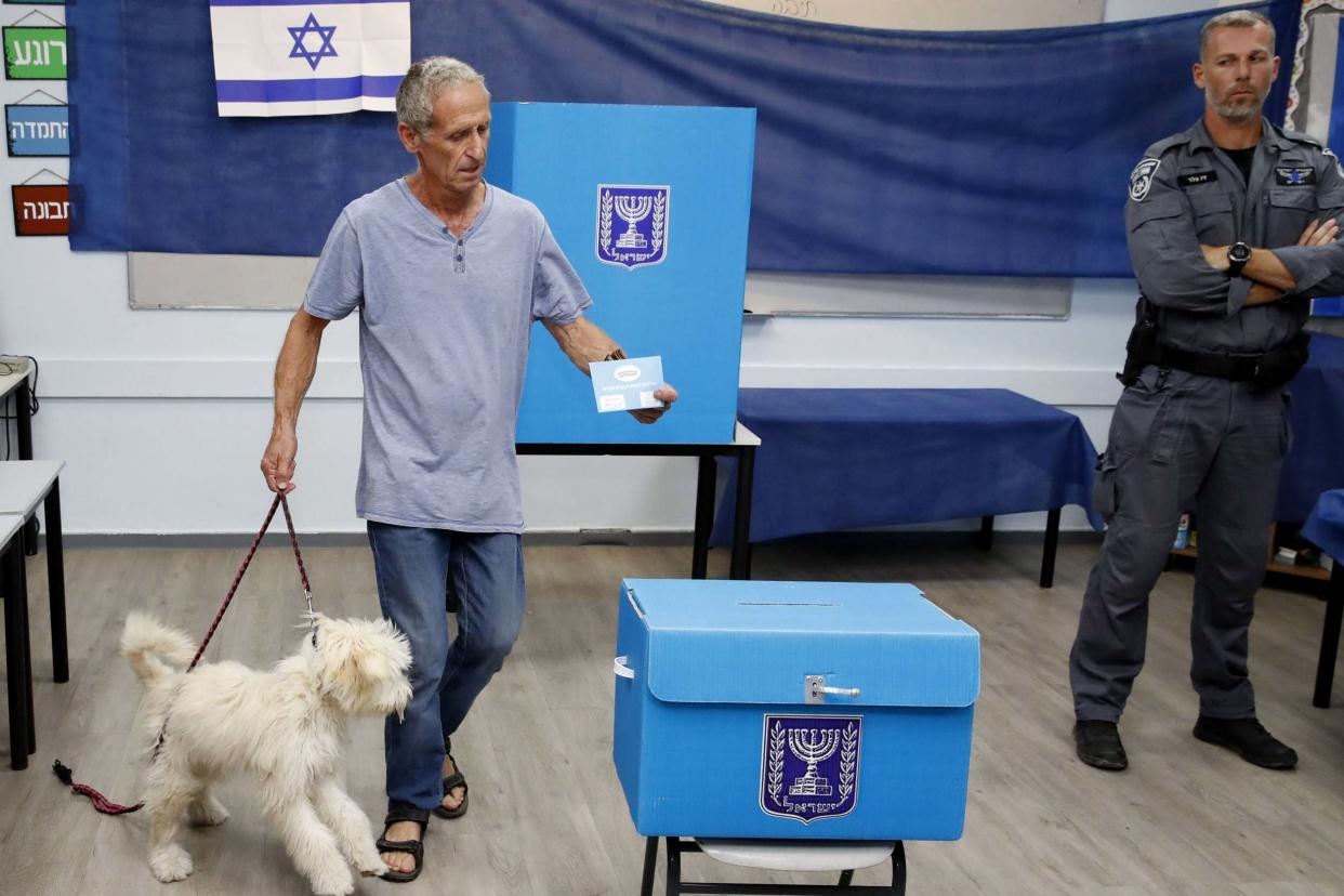 An Israeli man holds his dog while casting his ballot during Israel's parliamentary election at a polling station in Rosh Haayin: AFP/Getty Images