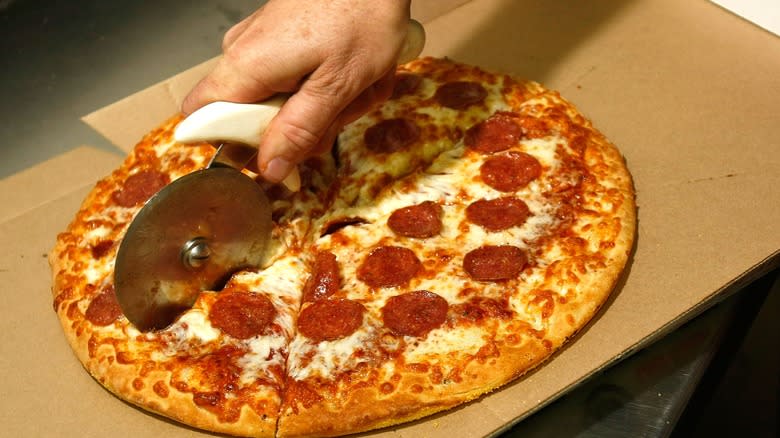 pepperoni pizza being sliced