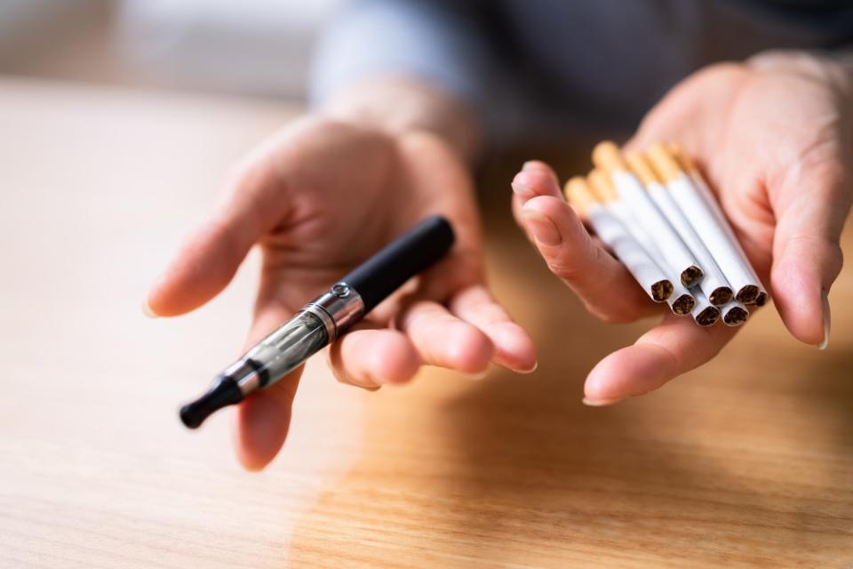 A person choosing between cigarettes and vaping.