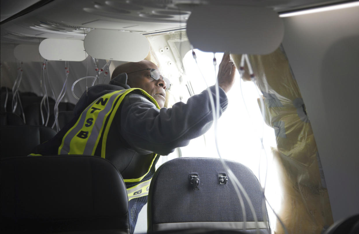 In this photo released by the National Transportation Safety Board, NTSB Investigator-in-Charge John Lovell examines the fuselage plug area of Alaska Airlines Flight 1282 on Sunday, Jan. 7, 2024, in Portland, Ore. A panel used to plug an area reserved for an exit door on the Boeing 737 Max 9 jetliner blew out Friday night shortly after the flight took off from Portland, forcing the plane to return to Portland International Airport. (National Transportation Safety Board via AP)