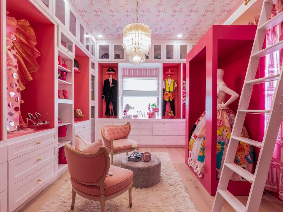 A pink closet with chairs and mannequins wearing clothes.