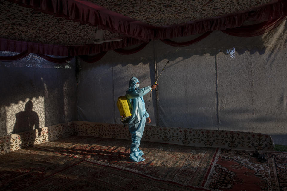A Kashmir man in personal protective equipment sprays disinfectant to sanitize a wedding tent on the outskirts of Srinagar, Indian controlled Kashmir, Thursday, Sept. 17, 2020. The coronavirus pandemic has changed the way people celebrate weddings in Kashmir. The traditional week-long feasting , elaborate rituals and huge gatherings have given way to muted ceremonies with a limited number of close relatives attending. With restrictions in place and many weddings cancelled, the traditional wedding chefs have little or no work. The virus has drastically impacted the life and businesses in the region. (AP Photo/ Dar Yasin)