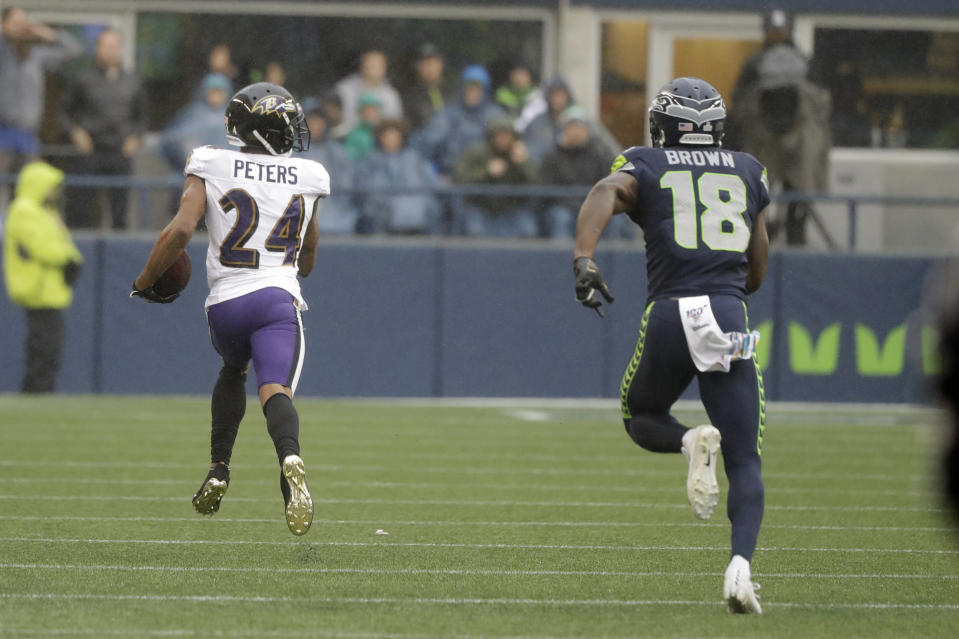 Baltimore Ravens cornerback Marcus Peters (24) runs for a touchdown after he intercepted a pass intended for Seattle Seahawks wide receiver Jaron Brown (18) during the first half of an NFL football game, Sunday, Oct. 20, 2019, in Seattle. (AP Photo/Elaine Thompson)