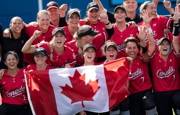 Canada’s women’s softball team poses for a photo with the Canadian flag after their win on Tuesday over Mexico in the bronze medal game at the Tokyo Olympics. (Adrian Wyld/The Canadian Press - image credit)