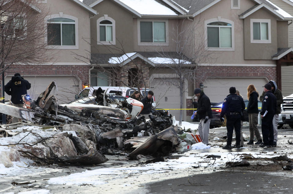 Emergency crews look through the debris from a small plane that crashed in a Roy, Utah, residential neighborhood, narrowly missing townhouses in the area, on Wednesday, Jan. 15, 2020. Roy police Sgt. Matthew Gwynn said the 64-year-old pilot was making a short flight from Bountiful to Ogden in a twin-engine Cessna Wednesday but crashed in the city of Roy about 30 miles north of Salt Lake City. (Steve Griffin/The Deseret News via AP)
